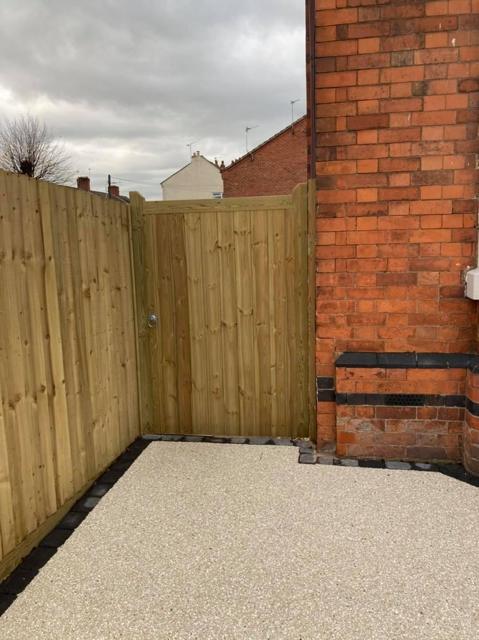 Timber gate and close-boarded fence beside a resin driveway