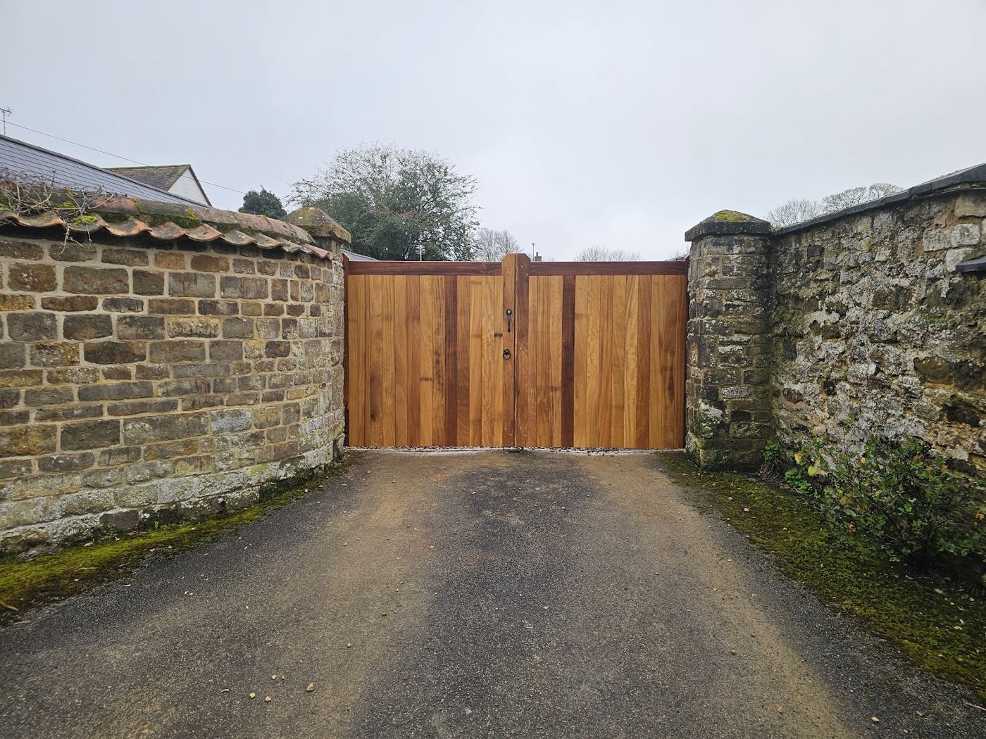 Timber driveway gates set into a stone wall