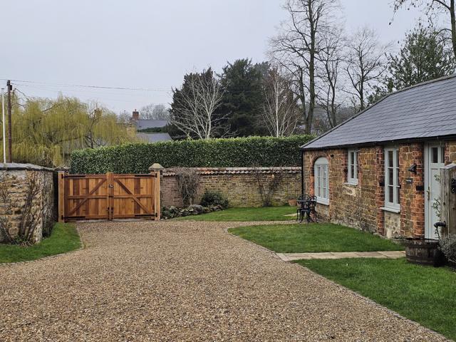 Oak driveway gate at a cottage entrance, hedges either side