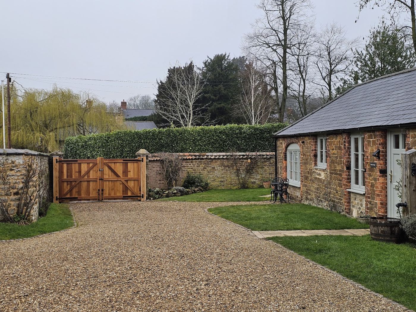 Oak driveway gate at a cottage entrance, hedges either side