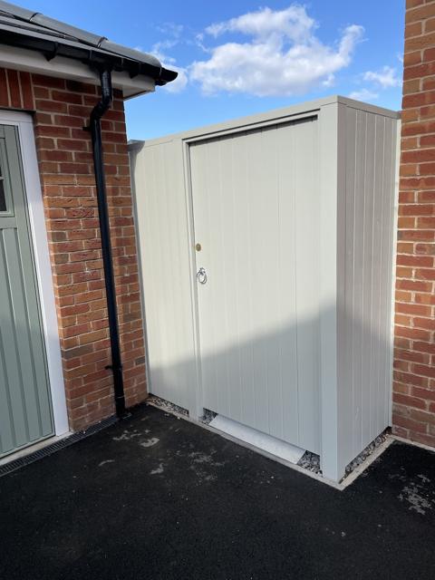 Pale grey side gate against a red brick wall